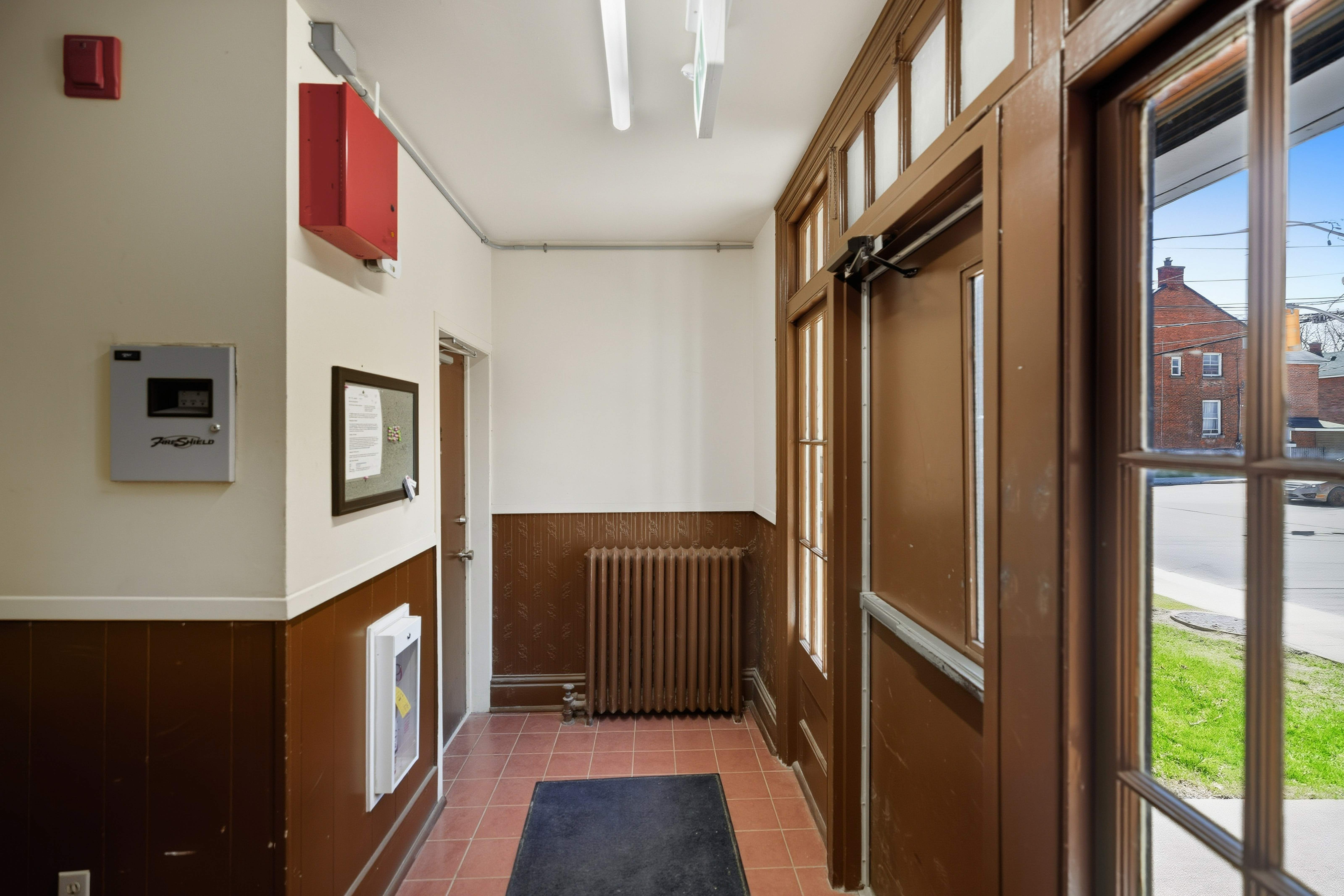 A hallway with a brown door and a black mat on the floor.